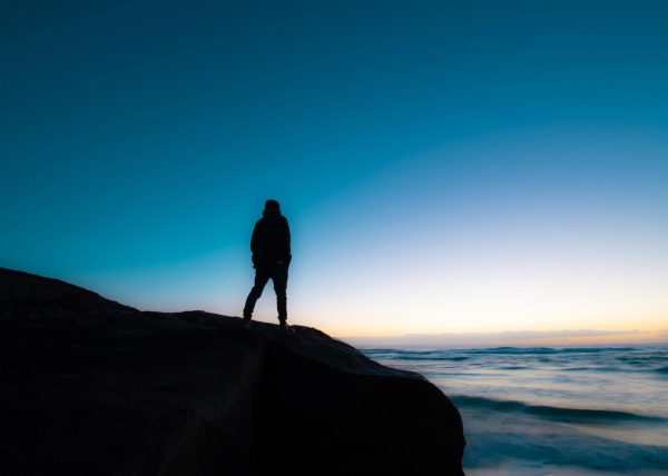 Person standing on cliff looking out to sea